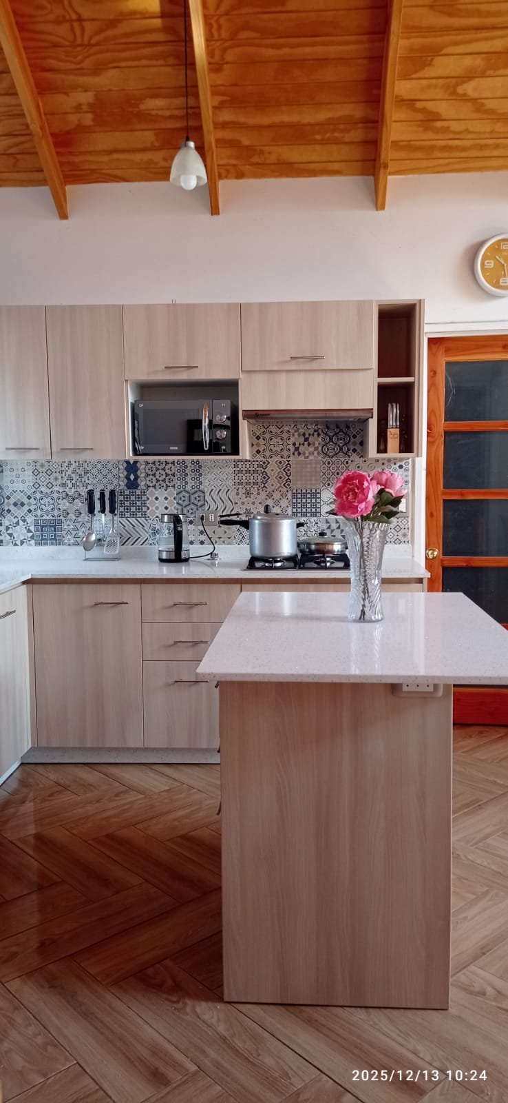 Cocina de melamina a la medida con módulos base, aéreos e isla central con cubierta de cuarzo, instalada en Santiago